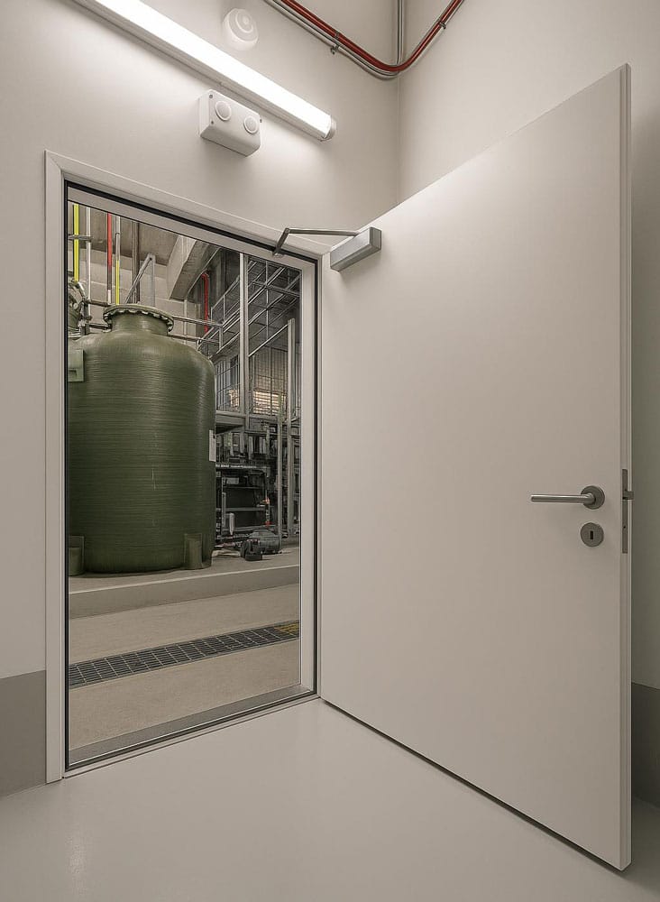 Watertight steel door open onto a plant room with a large storage tank