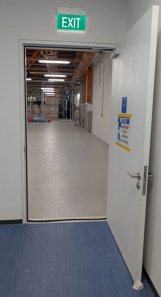 Watertight steel door open onto a corridor, EXIT sign above